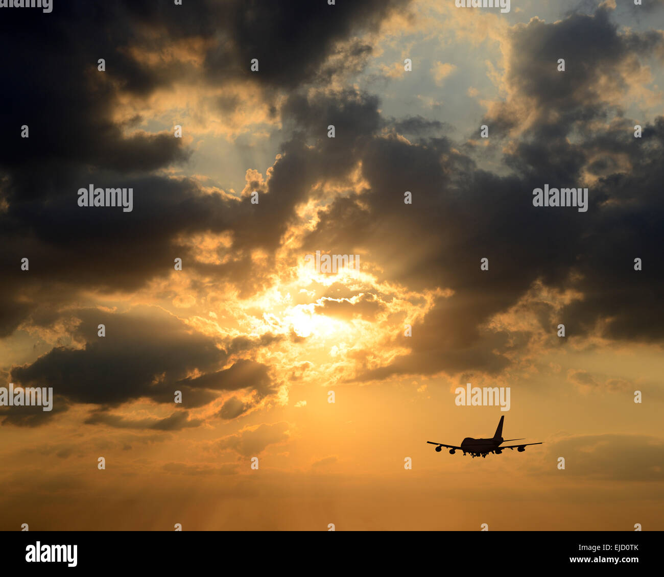 Airplane Silhouetted Against a Sunset. Stock Photo