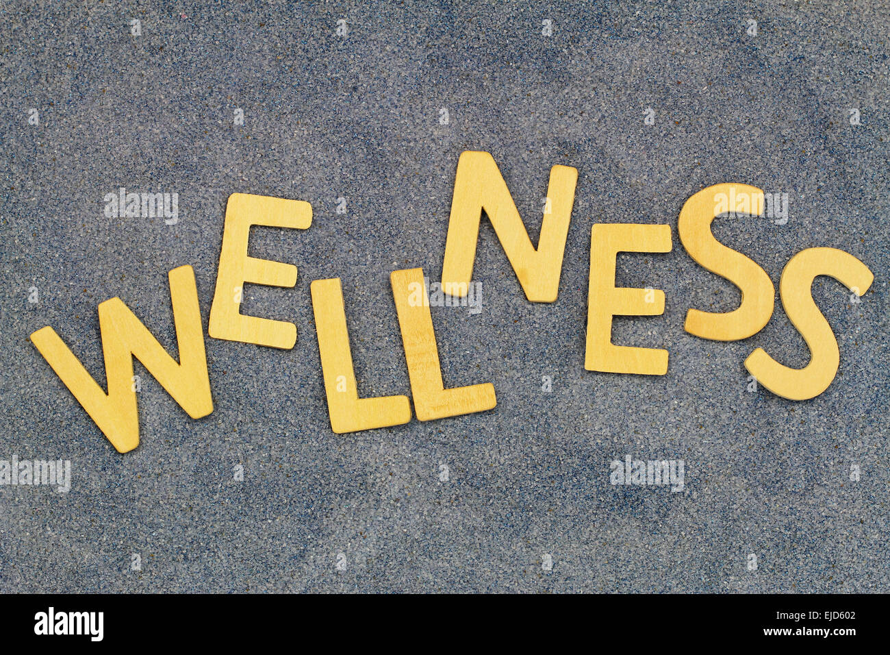Wellness written with wooden letters on blue sand Stock Photo