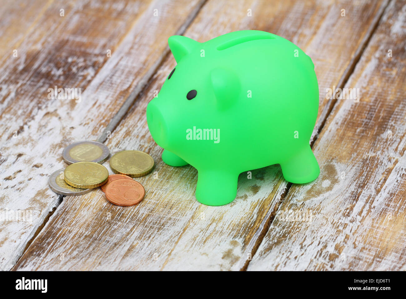 Piggy bank with coins on rustic surface Stock Photo - Alamy