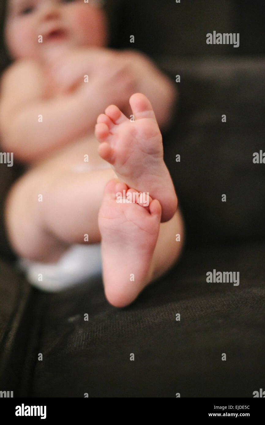 A baby lying on a sofa, wearing a diaper. Stock Photo