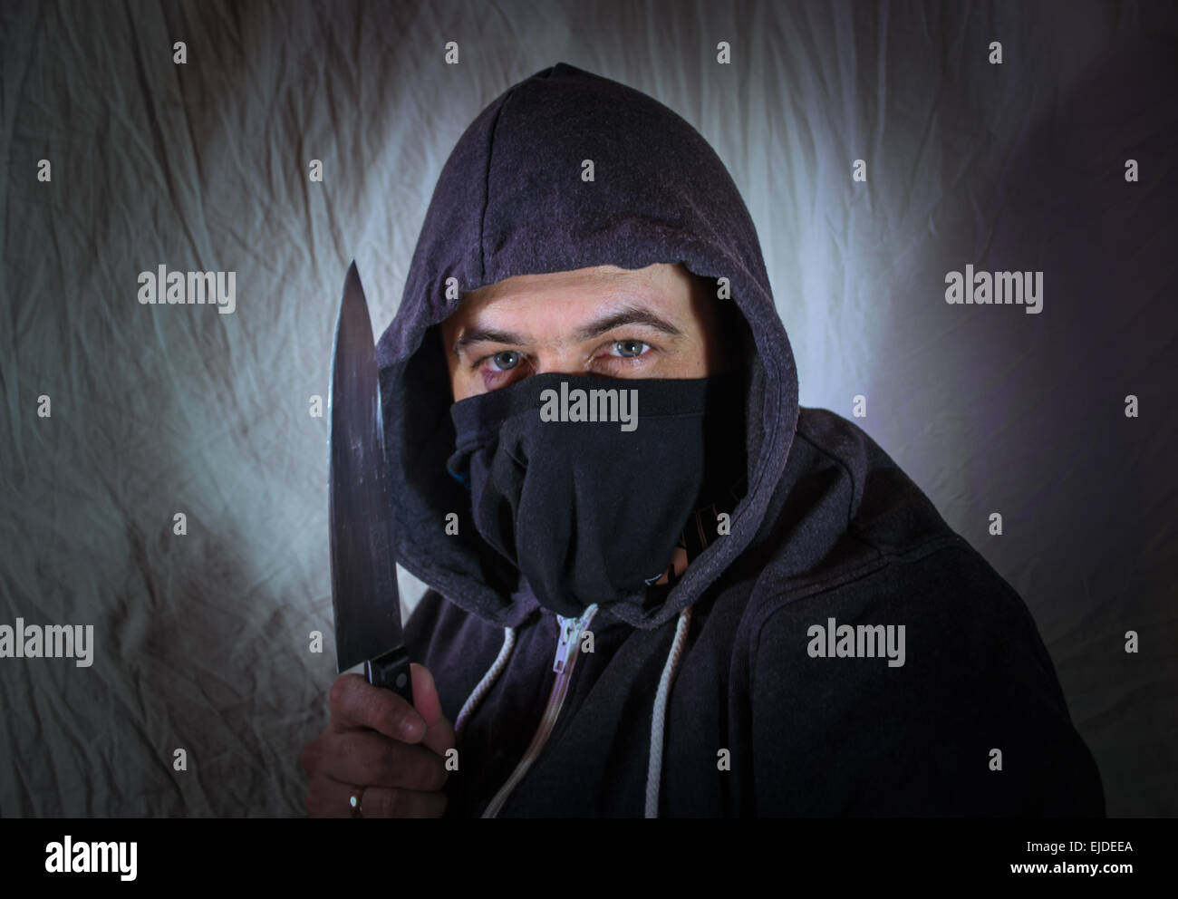 a-masked-intruder-with-a-kitchen-knife-glares-with-menace-EJDEEA.jpg