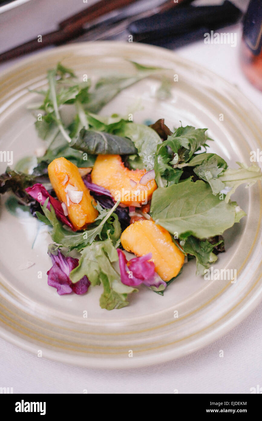 A plate of fresh salad leaves and slices of fresh peach fruit. Stock Photo