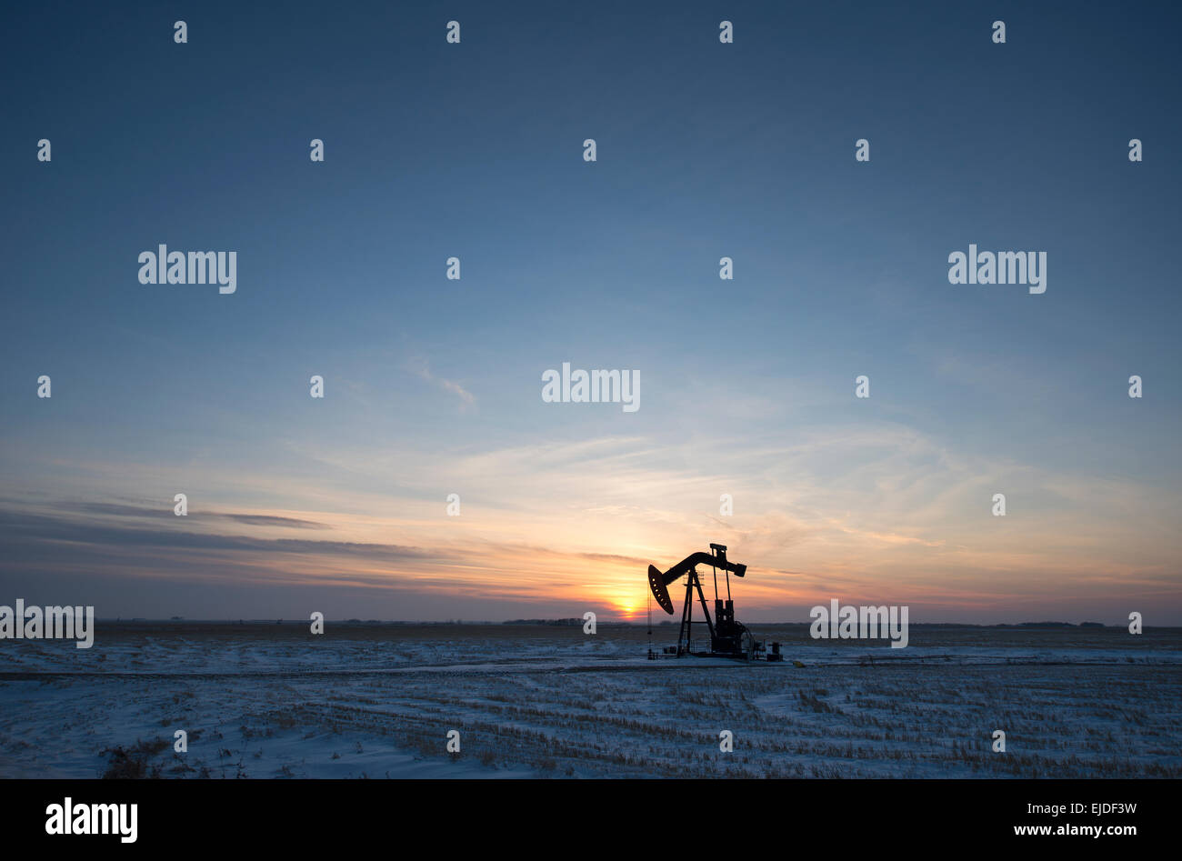 An oil drilling rig and pumpjack on a flat plain in the Canadian oil ...