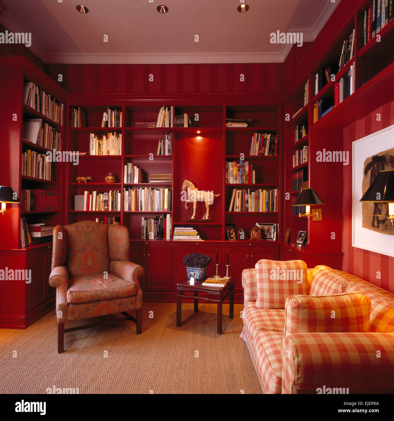 Sisal carpet and upholstered armchair and sofa in red nineties living room with fitted bookshelves Stock Photo