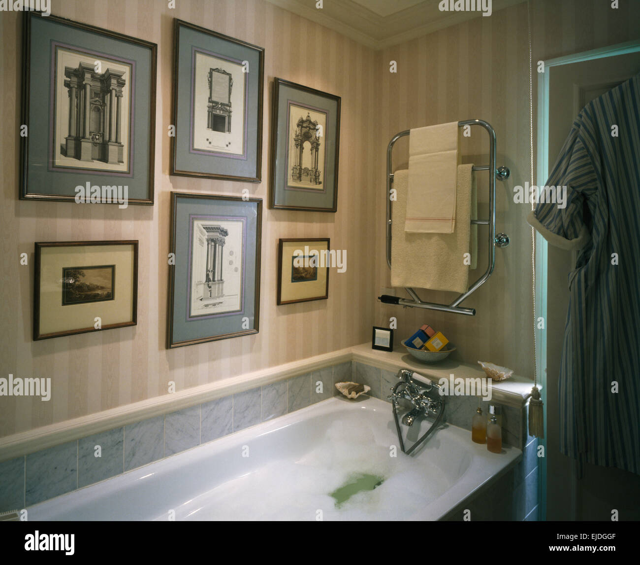 Framed architectural drawings on wall above bath in bathroom