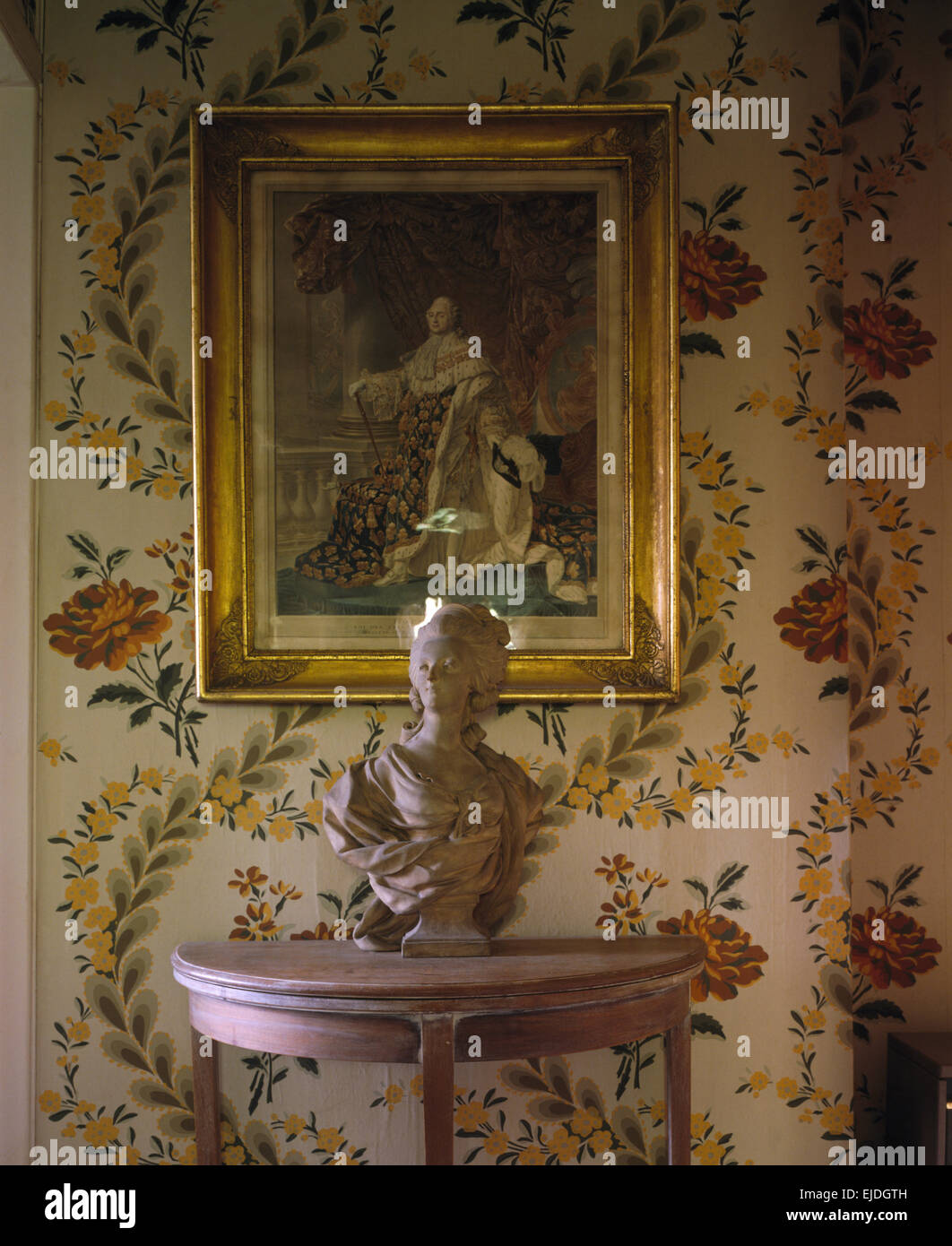 Picture on wall above a painted console table with a Georgian style marble bust in a nineties hall with floral wallpaper Stock Photo