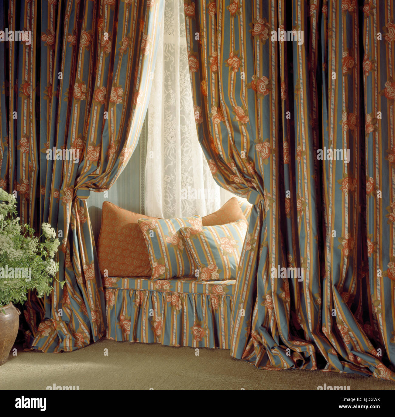 Heavy drapes on window with matching cushions on the window seat in nineties bedroom Stock Photo
