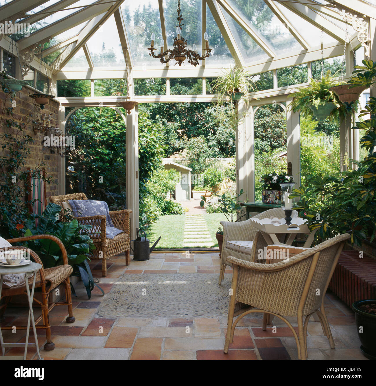 Wicker chairs in conservatory with doors open to the garden Stock Photo
