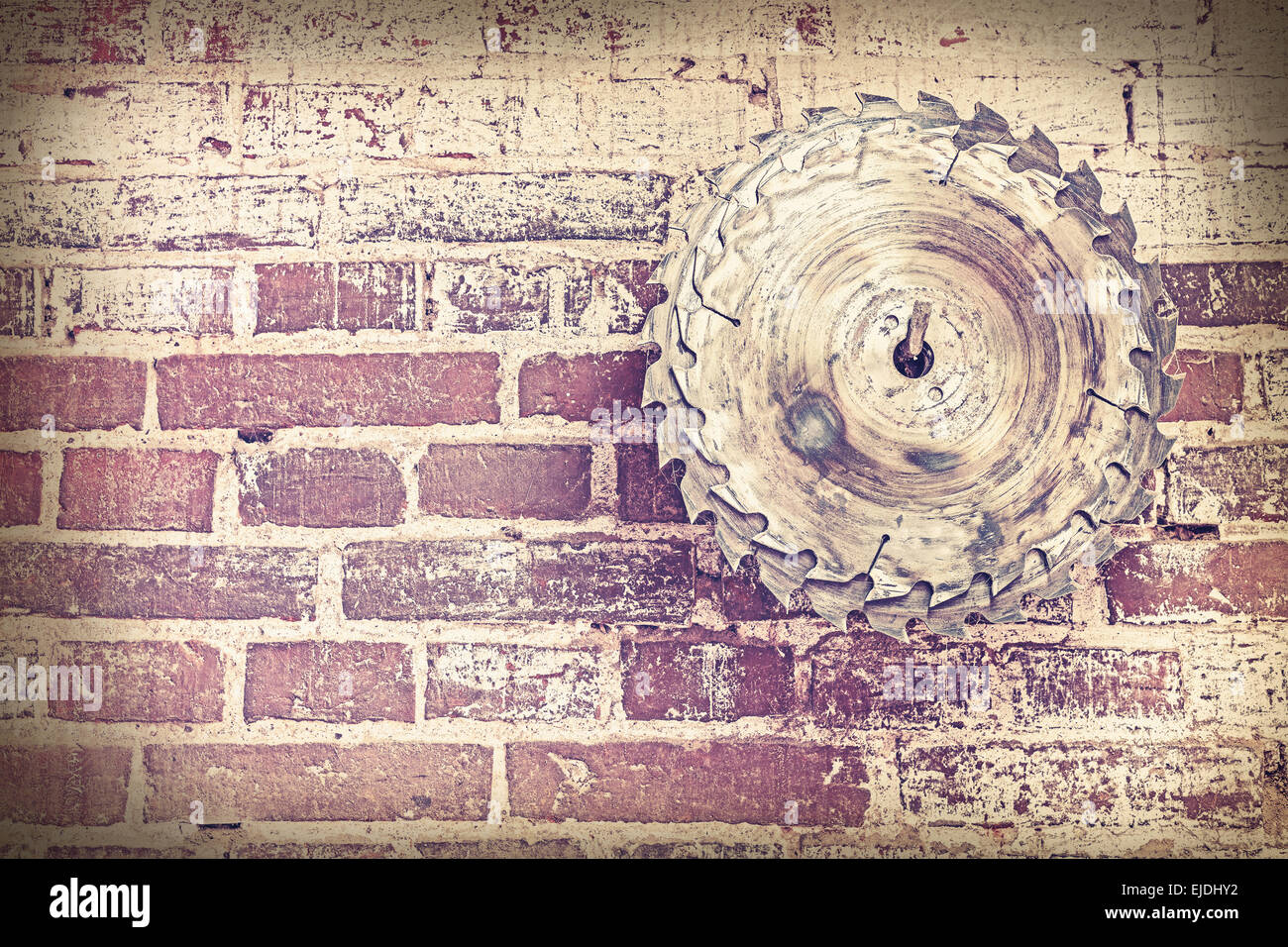 Retro style circular saw blade on a grungy brick wall. Stock Photo