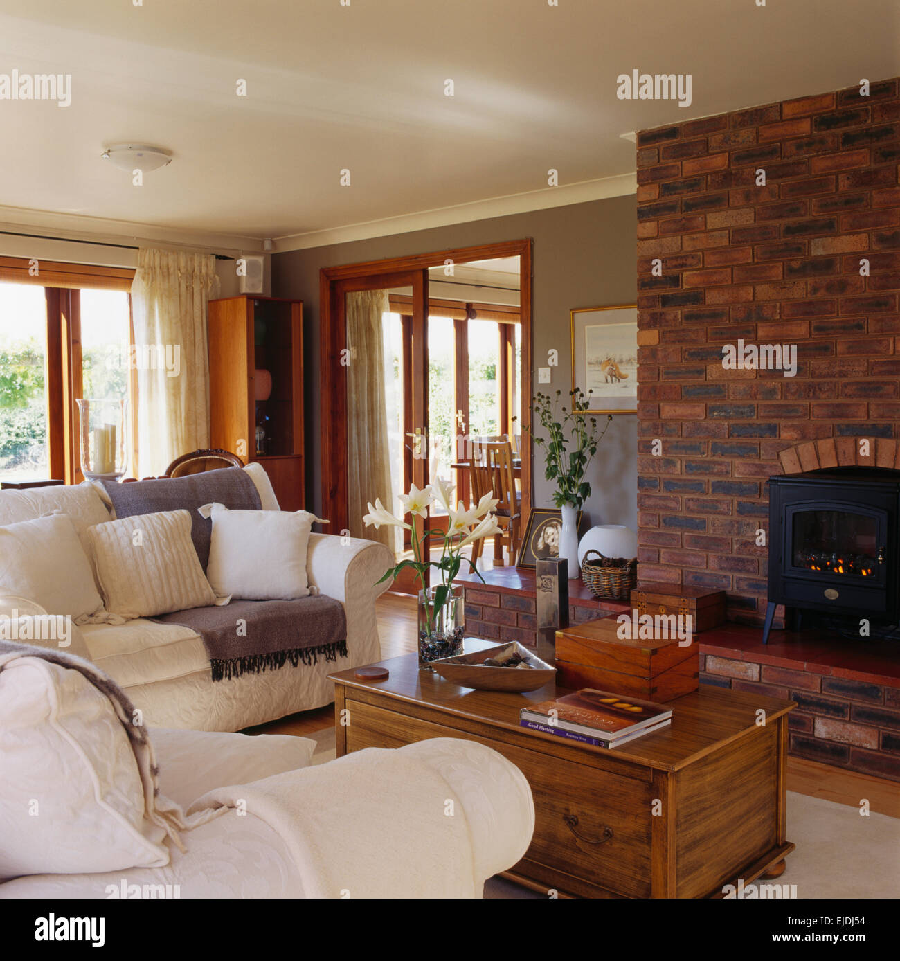 White Sofas And Old Pine Chest Around Fireplace With Wood Burning