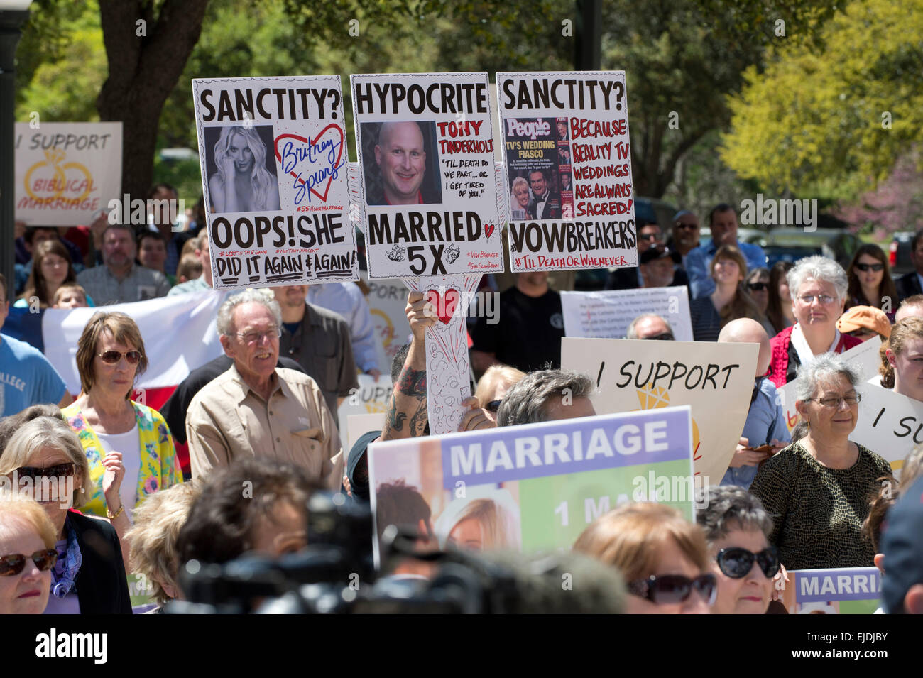 A counter protester holds a sign mocking the sanctity of marriage at a rally opposing gay marriage at Texas Capitol in Austin Stock Photo