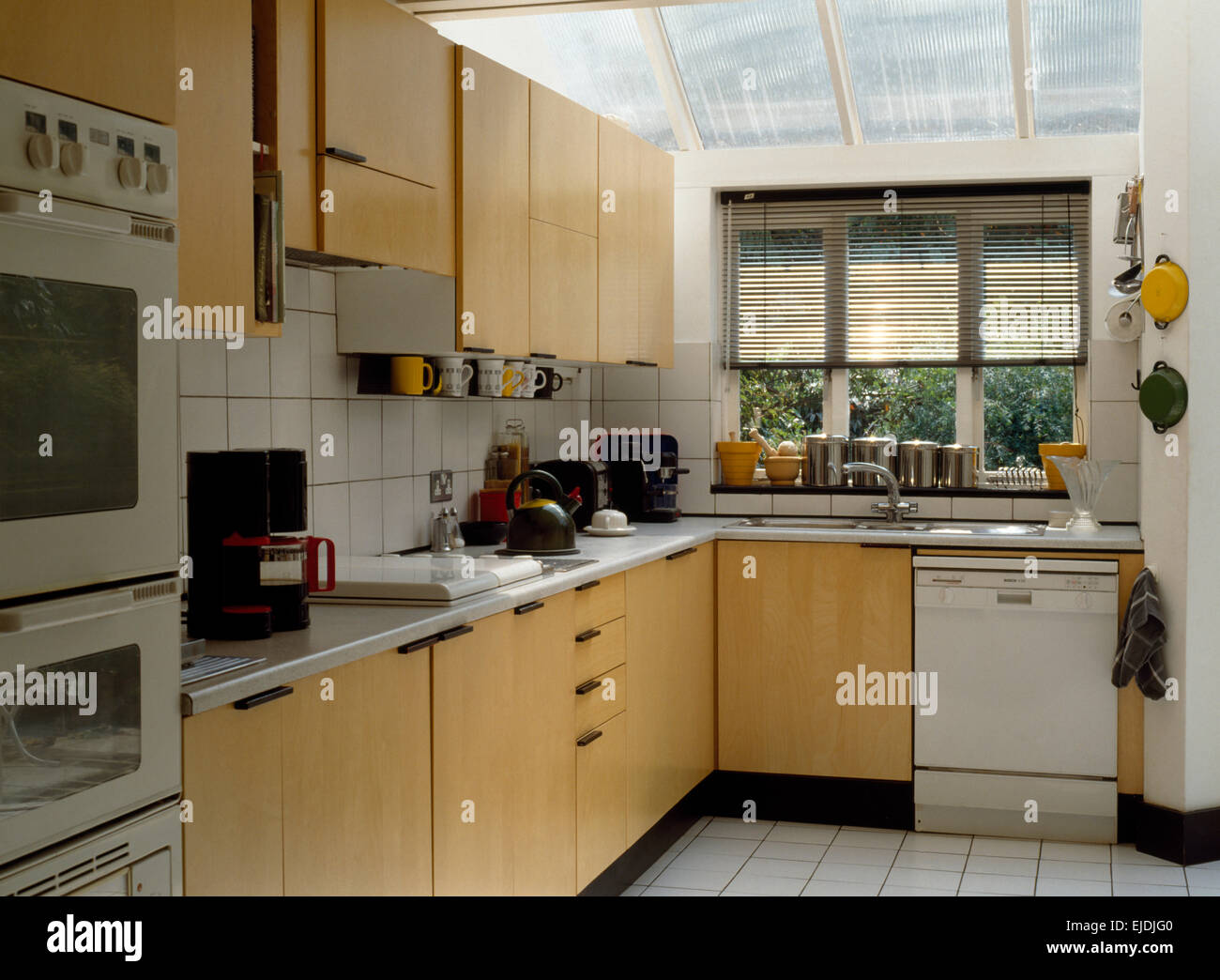 Interior of an nineties kitchen extension with fitted dishwasher below window with Venetian blind Stock Photo