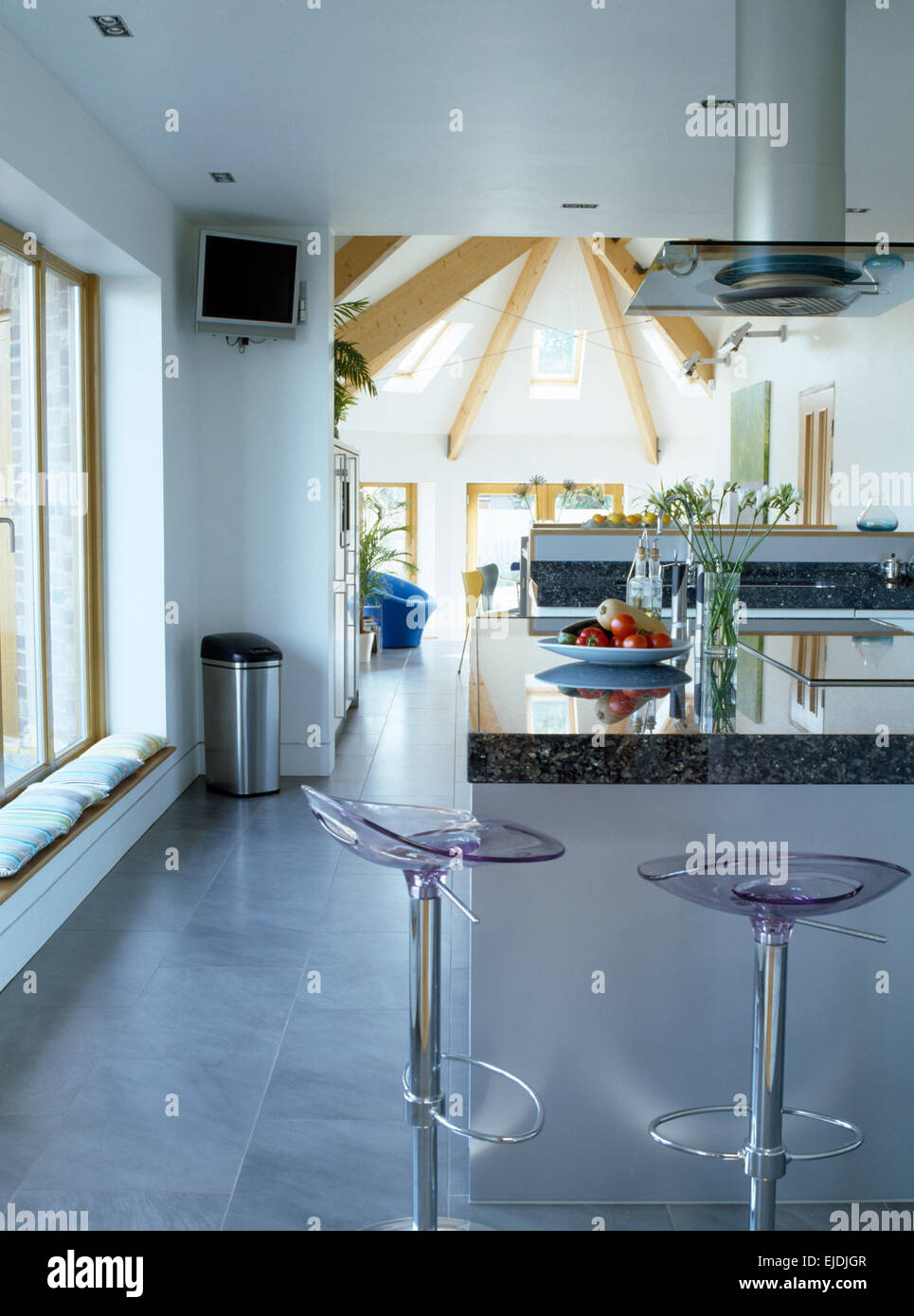 Perspex+chrome stools at breakfast bar in modern open plan kitchen Stock Photo