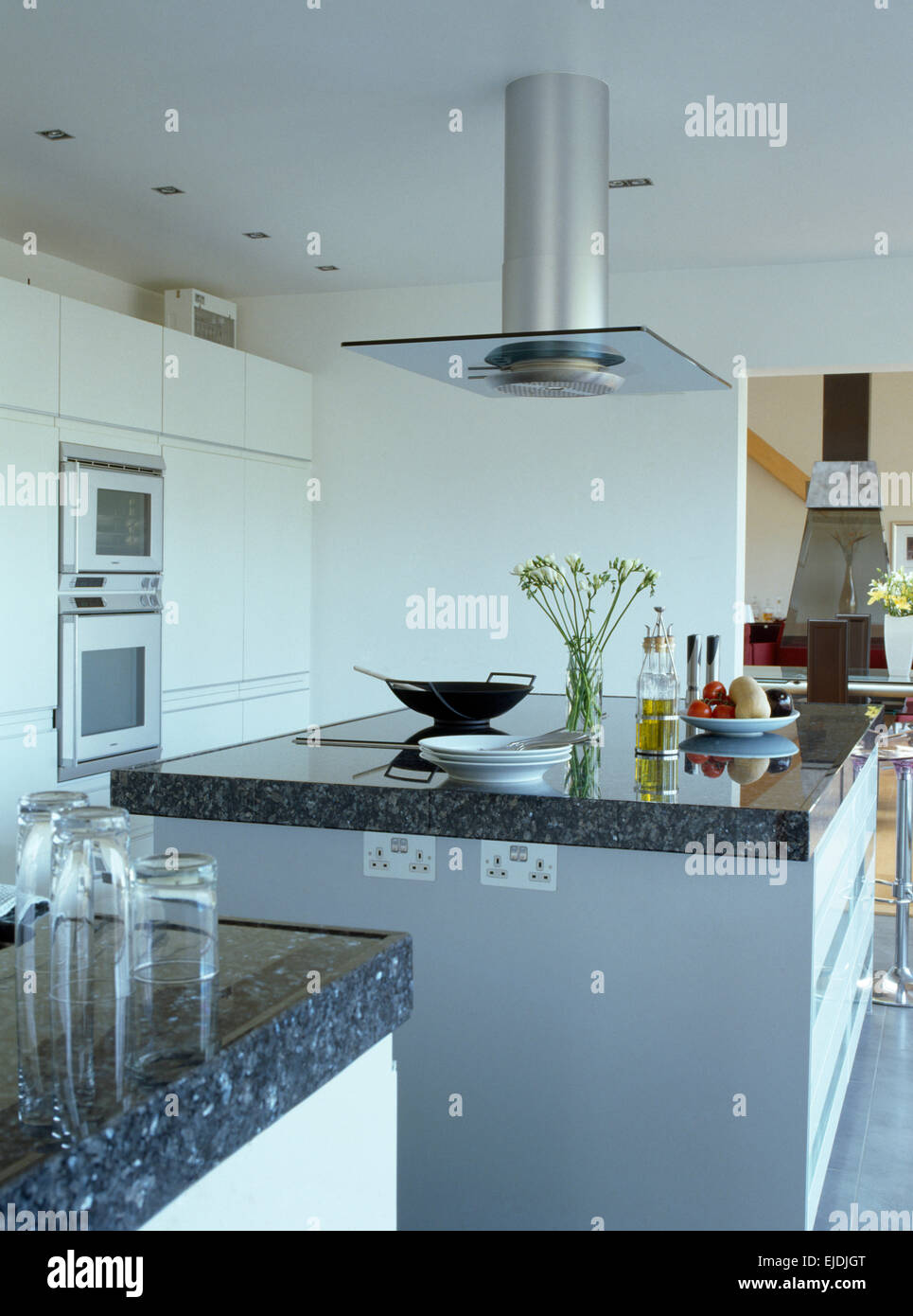 Chrome extractor above granite topped island unit in modern kitchen Stock Photo