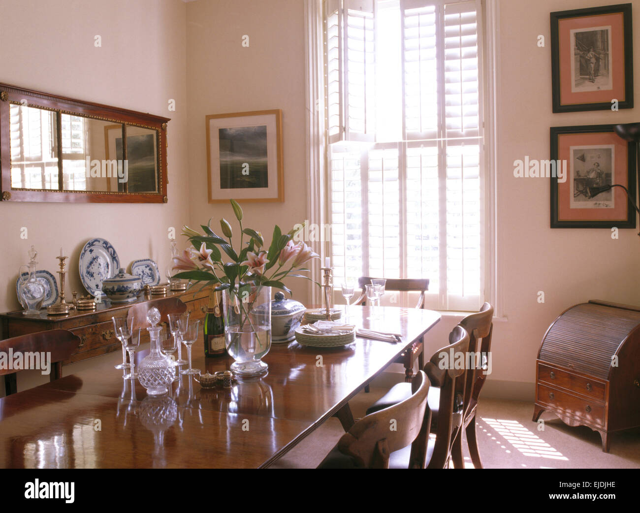 Glassware on table in traditional dining room with plantation shutters on the window Stock Photo