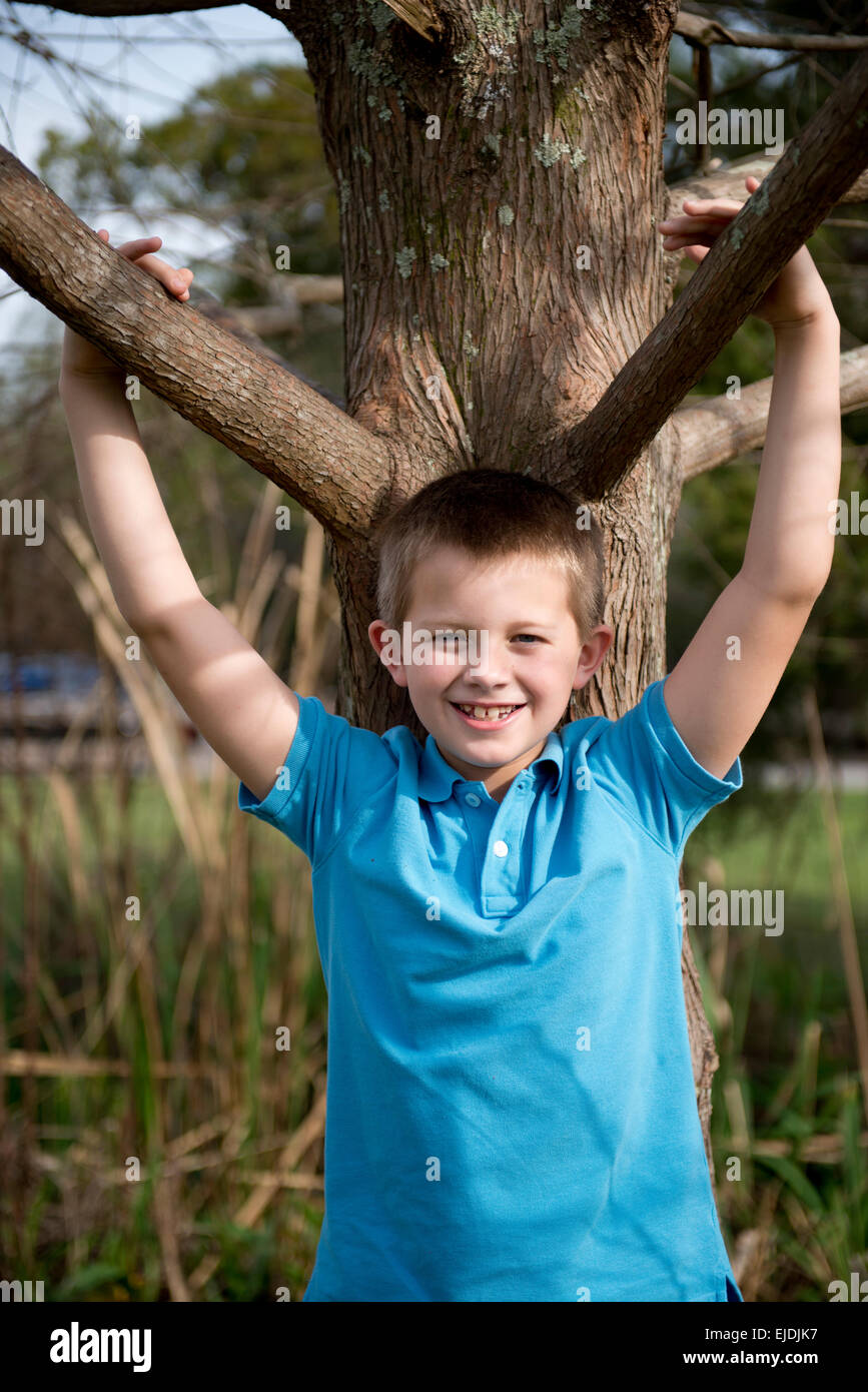 Young boy leaning on oak tree at park, portrait Stock Photo