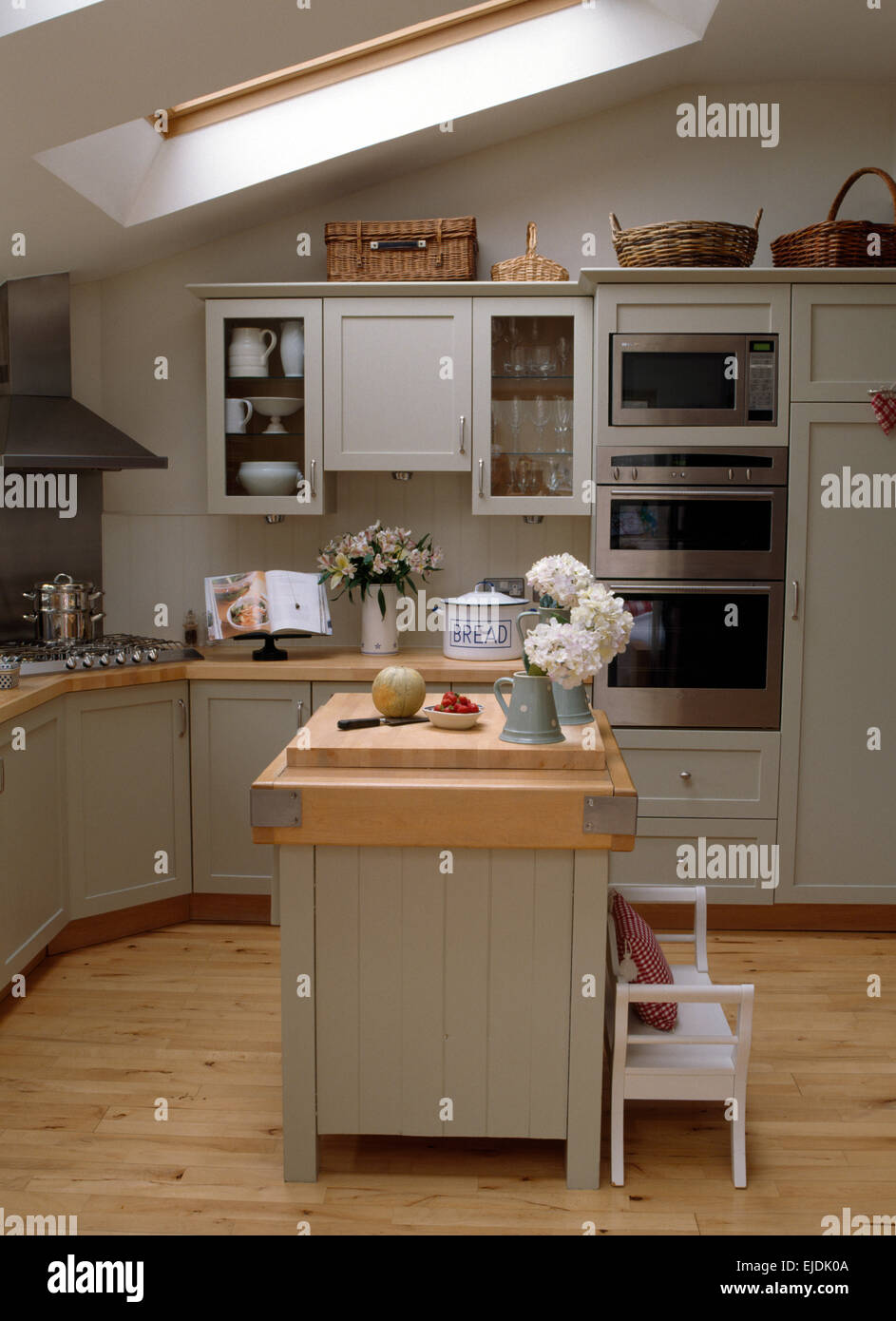 Beech worktop on island unit in country kitchen extension with pale gray fitted units Stock Photo