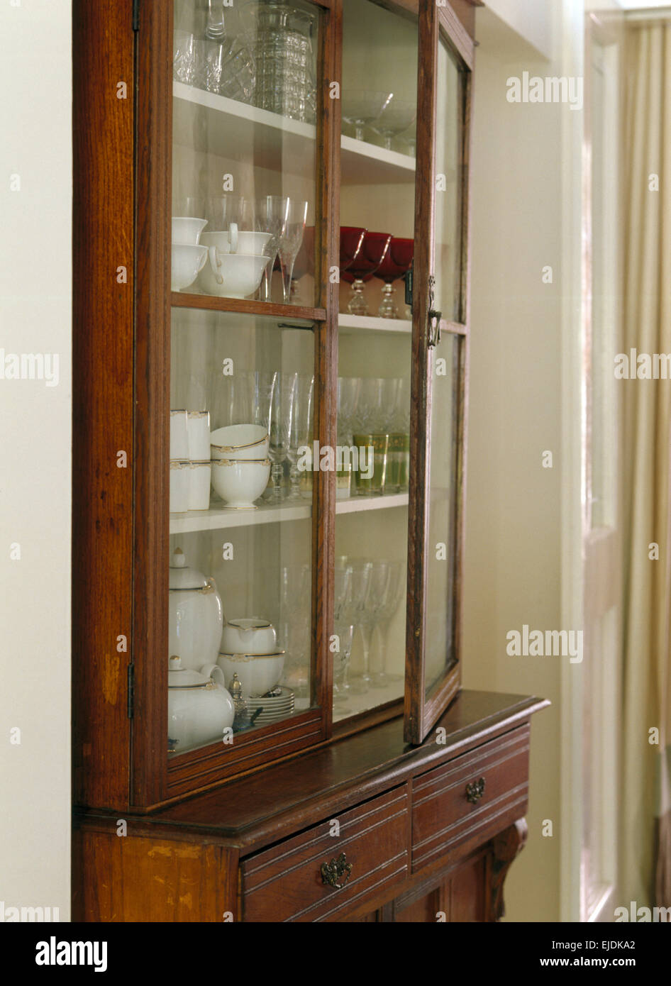 Close Up Of Antique Glass Front Dresser With Glassware And White