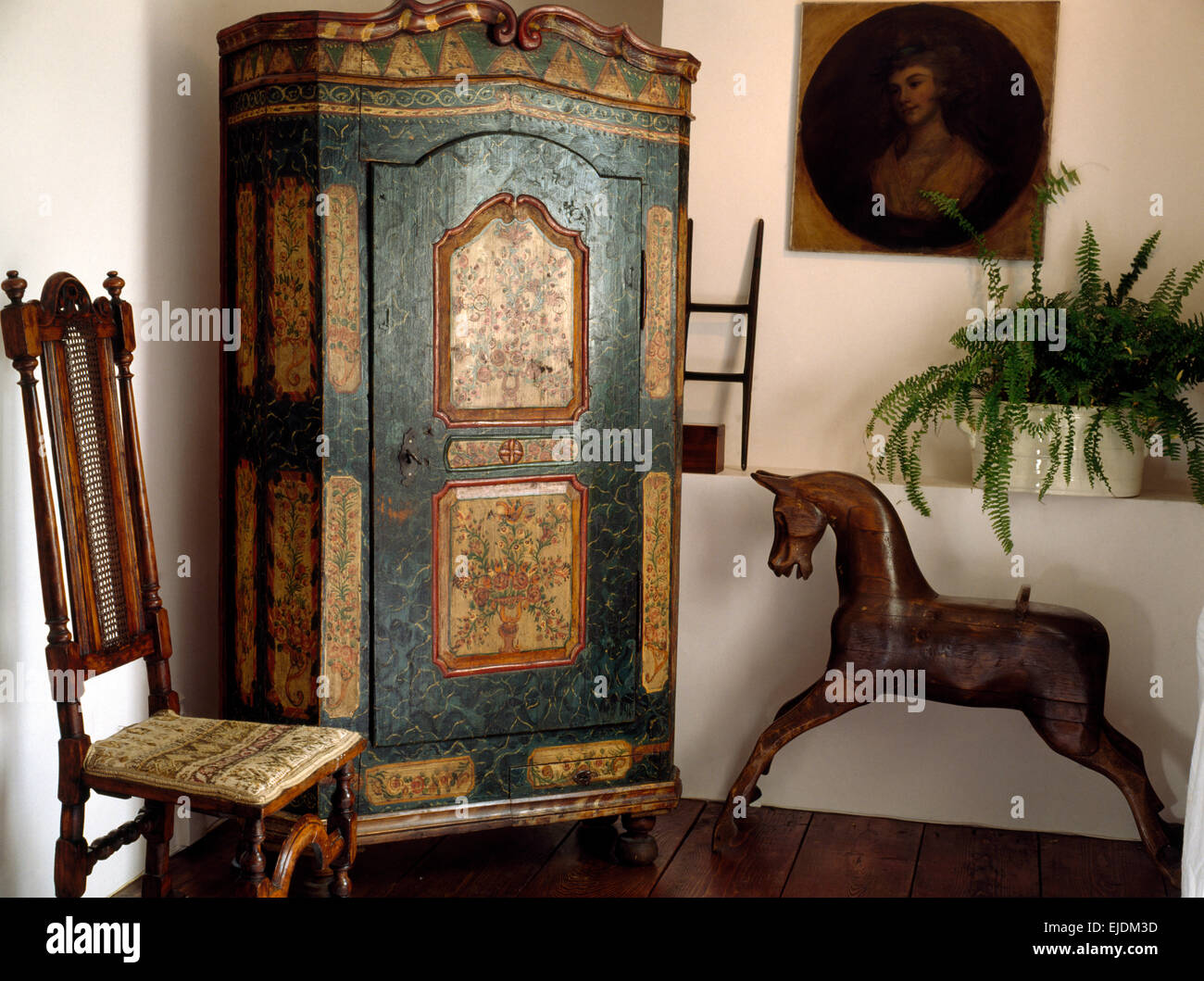 Painted antique French cupboard and rocking horse in cottage hall Stock Photo