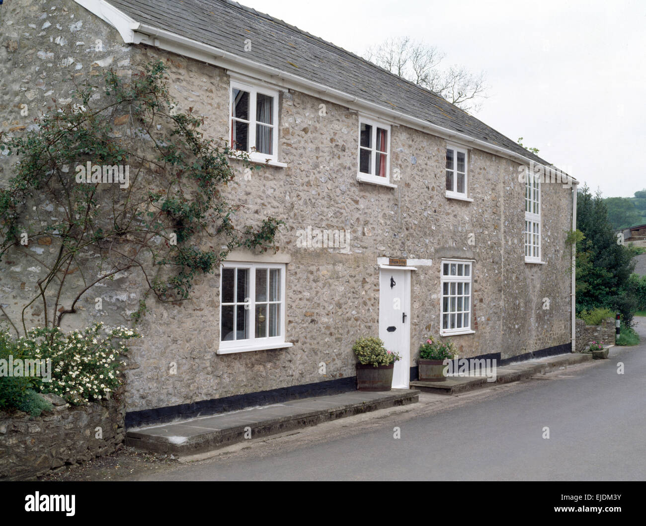 Exterior of stone country house with white painted windows and front door Stock Photo