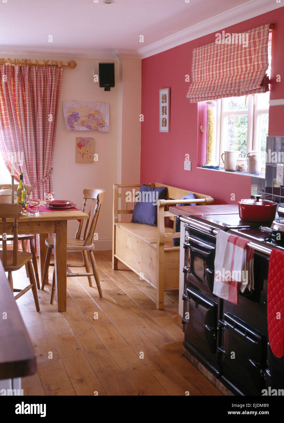Black Aga and wooden flooring in pink nineties kitchen dining room Stock Photo