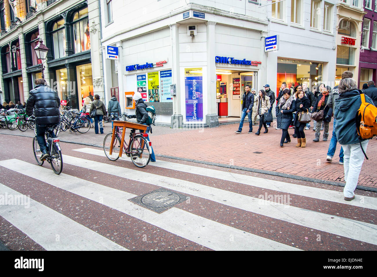 Resourceful young woman walking a table that she has purchased home atop her bicycle in Amsterdam. Stock Photo