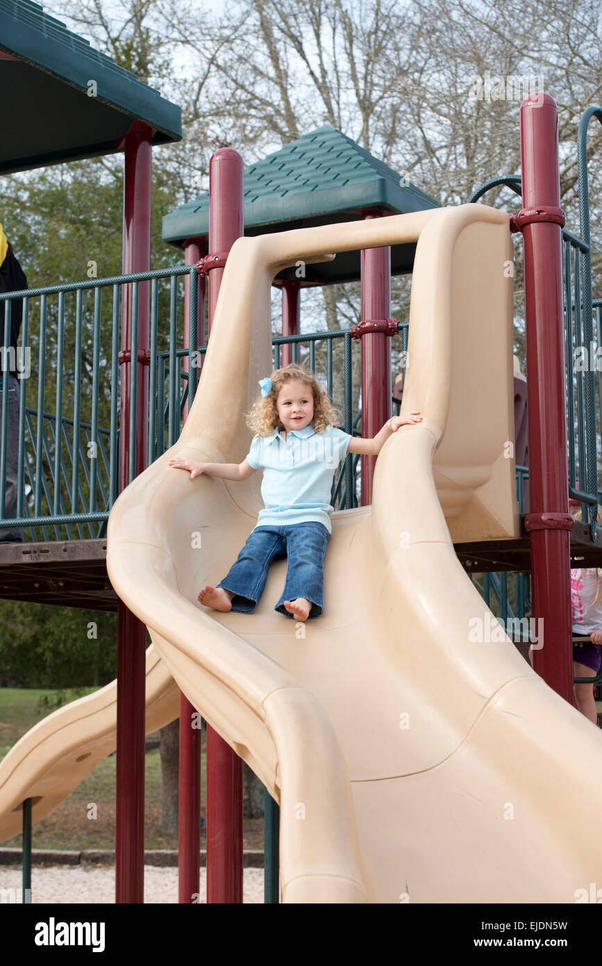 Young girl goes down slide at park playground Stock Photo - Alamy