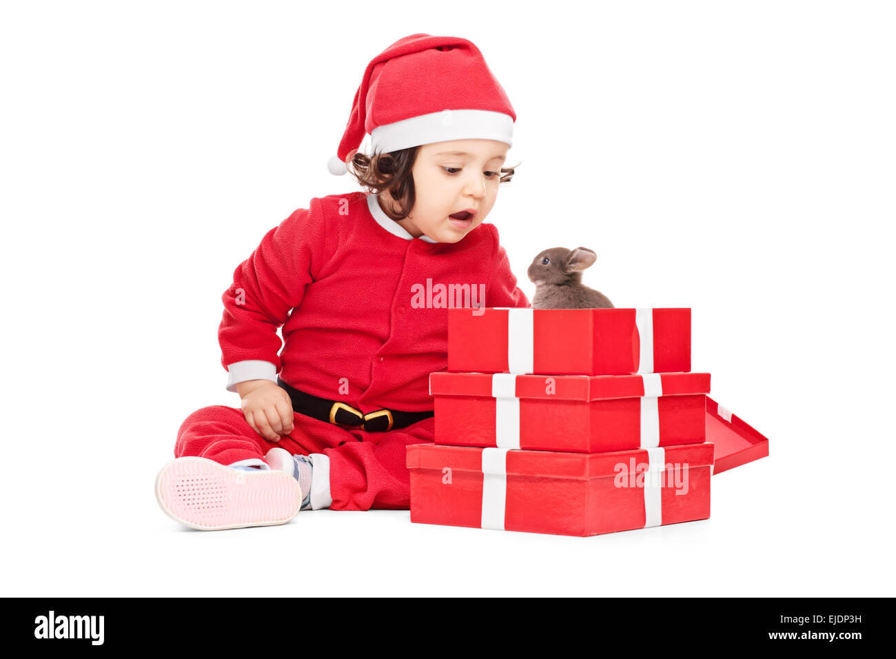 Adorable baby girl in Santa Claus costume opening the Christmas presents Stock Photo