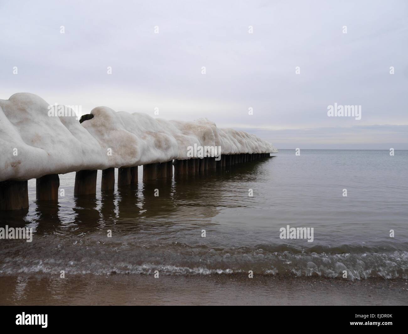 ice-covered breakwater on sea background Stock Photo