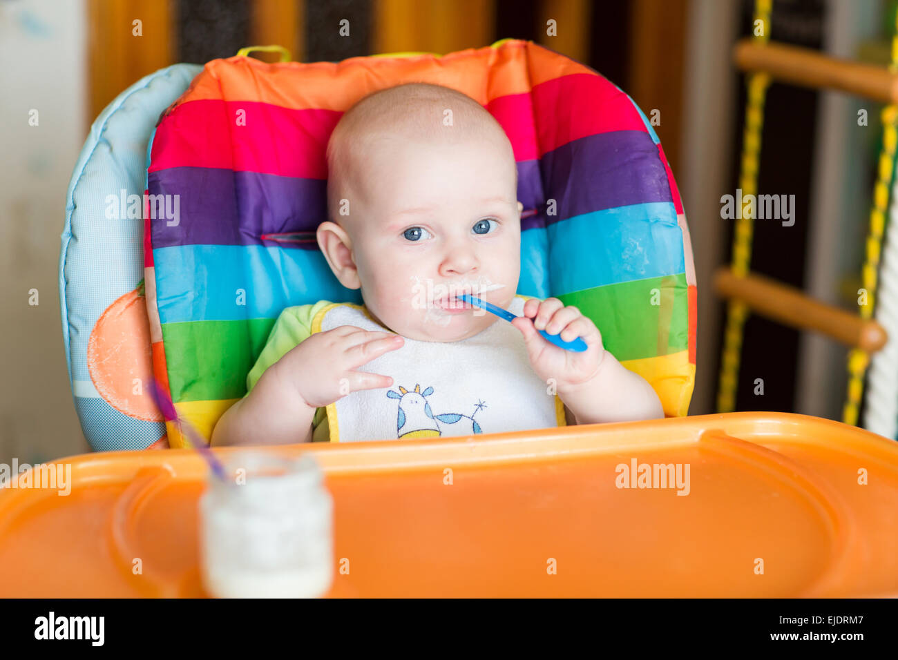 Adorable baby eating in high chair. Baby's first solid food Stock Photo Alamy