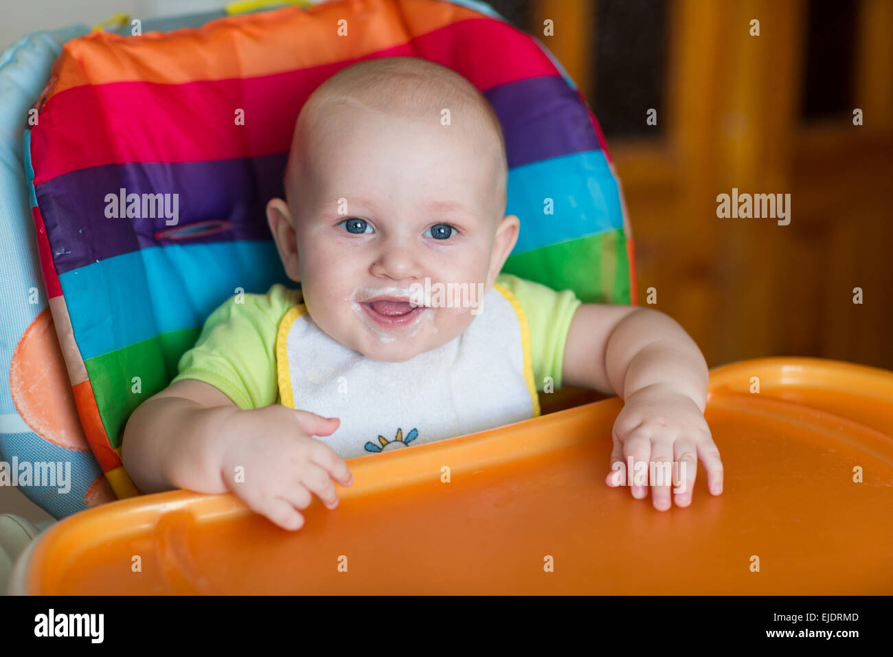 Adorable baby eating in high chair. Baby's first solid food Stock Photo