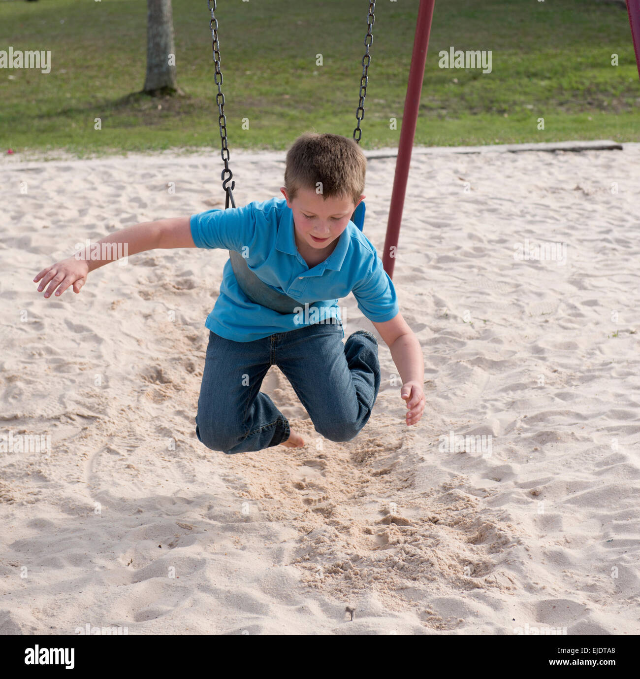 Eight year old boy swinging at park playground Stock Photo