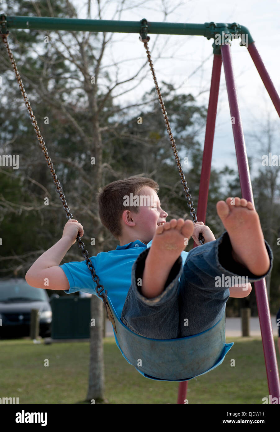 Eight year old boy swinging at a park playground Stock Photo