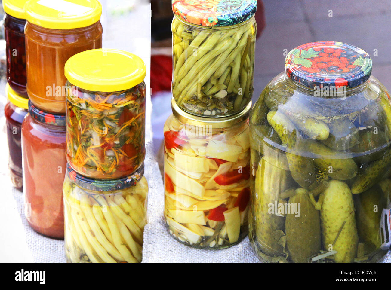 different vegetables pickles in glass jars containing paprika butter beans tomatoes cucumbers carrots cabbage Stock Photo