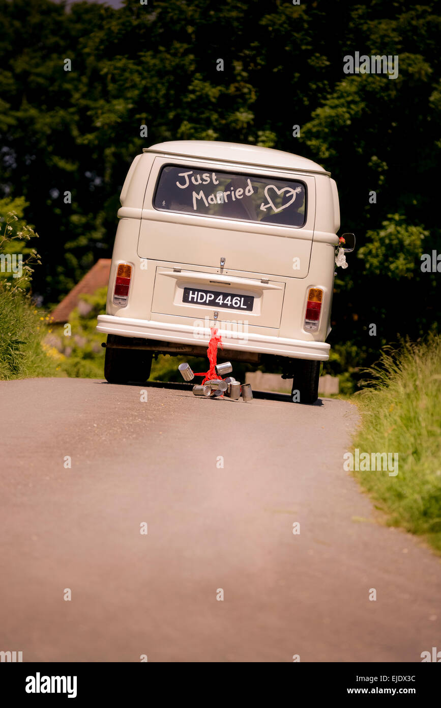 Volkswagen Camper bus with just married in the window being driven away with cans tied to the back bumper. Stock Photo