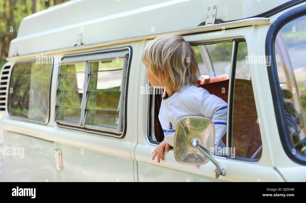 A young boy leans out of a Volkswagen Camper bus in East Sussex UK. Stock Photo