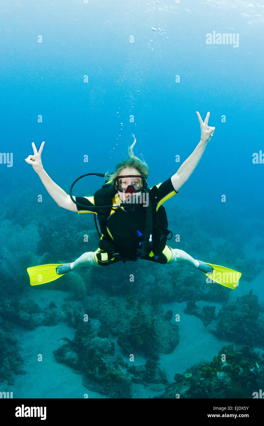 A female diver poses for the camera with peace signs, St. Lucia. Stock Photo
