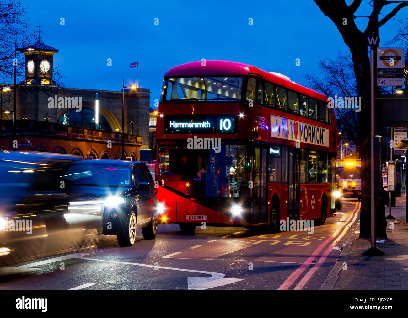Modern double decker red London bus at night next to a bus stop on Euston Road in central London England UK Stock Photo