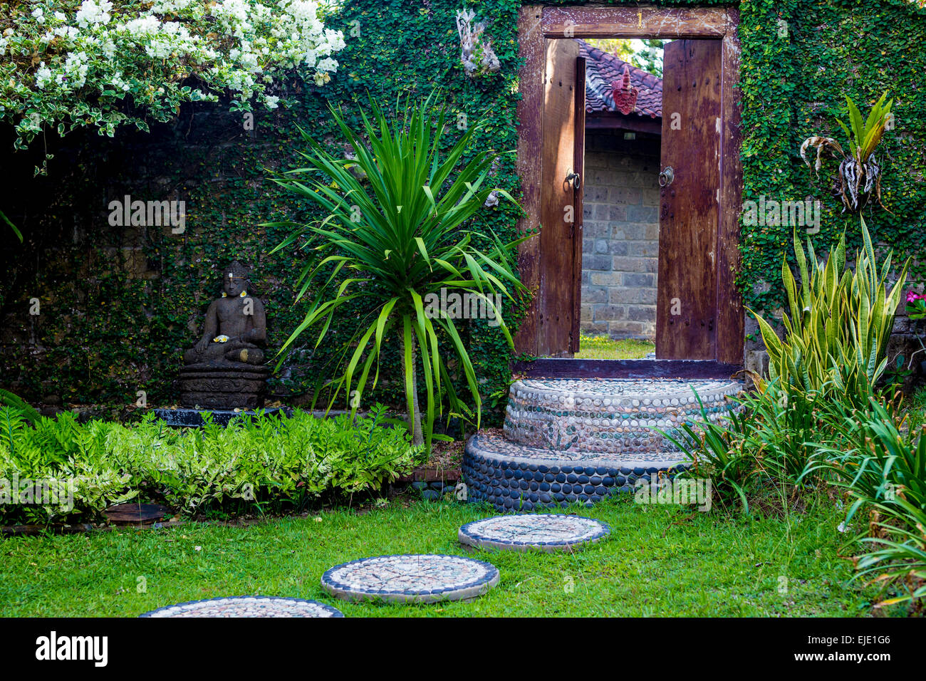 Door and Budha statue in the garden. Bali. Indonesia. Stock Photo