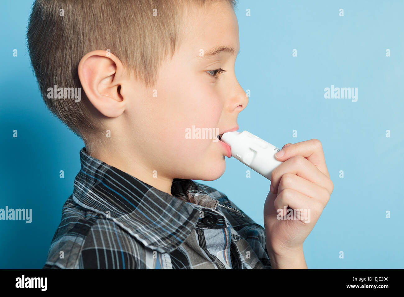 asthma boy with is inhalator over blue background Stock Photo