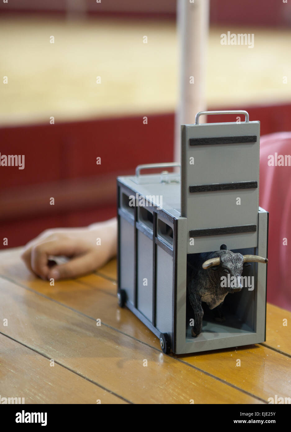 Child playing with a transport box for fighting bull toy over a wooden