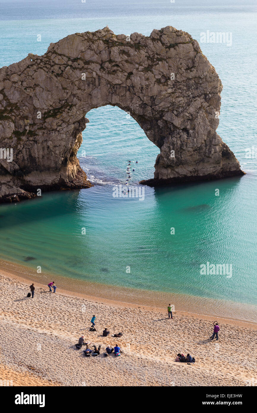 The sea arch at Durdle Door on the Jurassic coast in Dorset on a calm, sunny day. Swimmers swim through the arch. Stock Photo