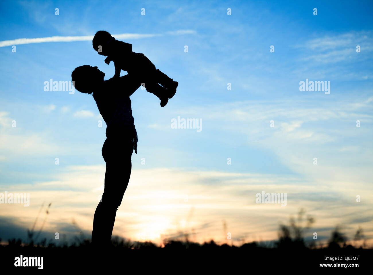 Mother holding baby up in the back lit, Stock Photo