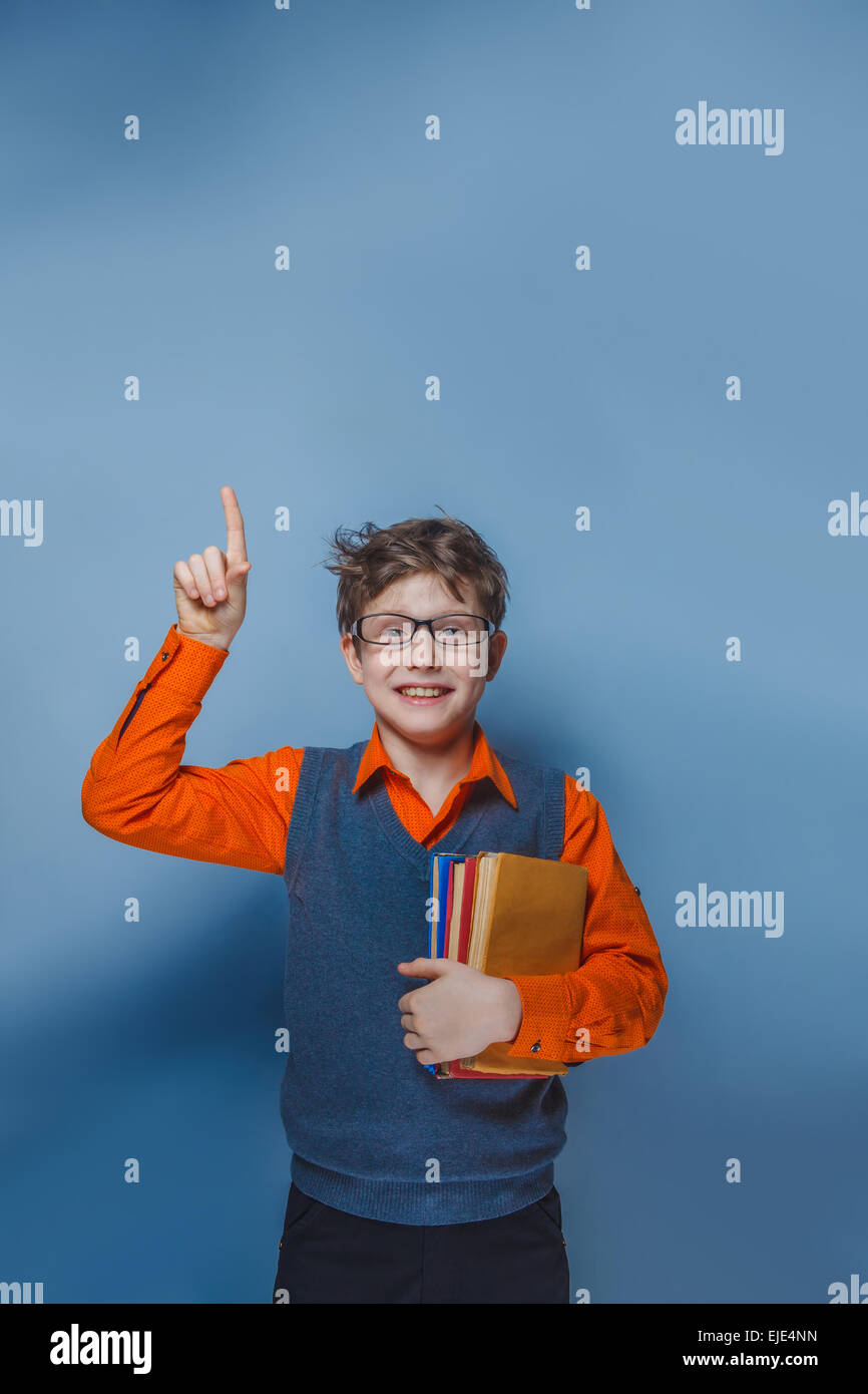 European-looking  boy of ten years in glasses thumbs up, the idea of the book on a blue background Stock Photo
