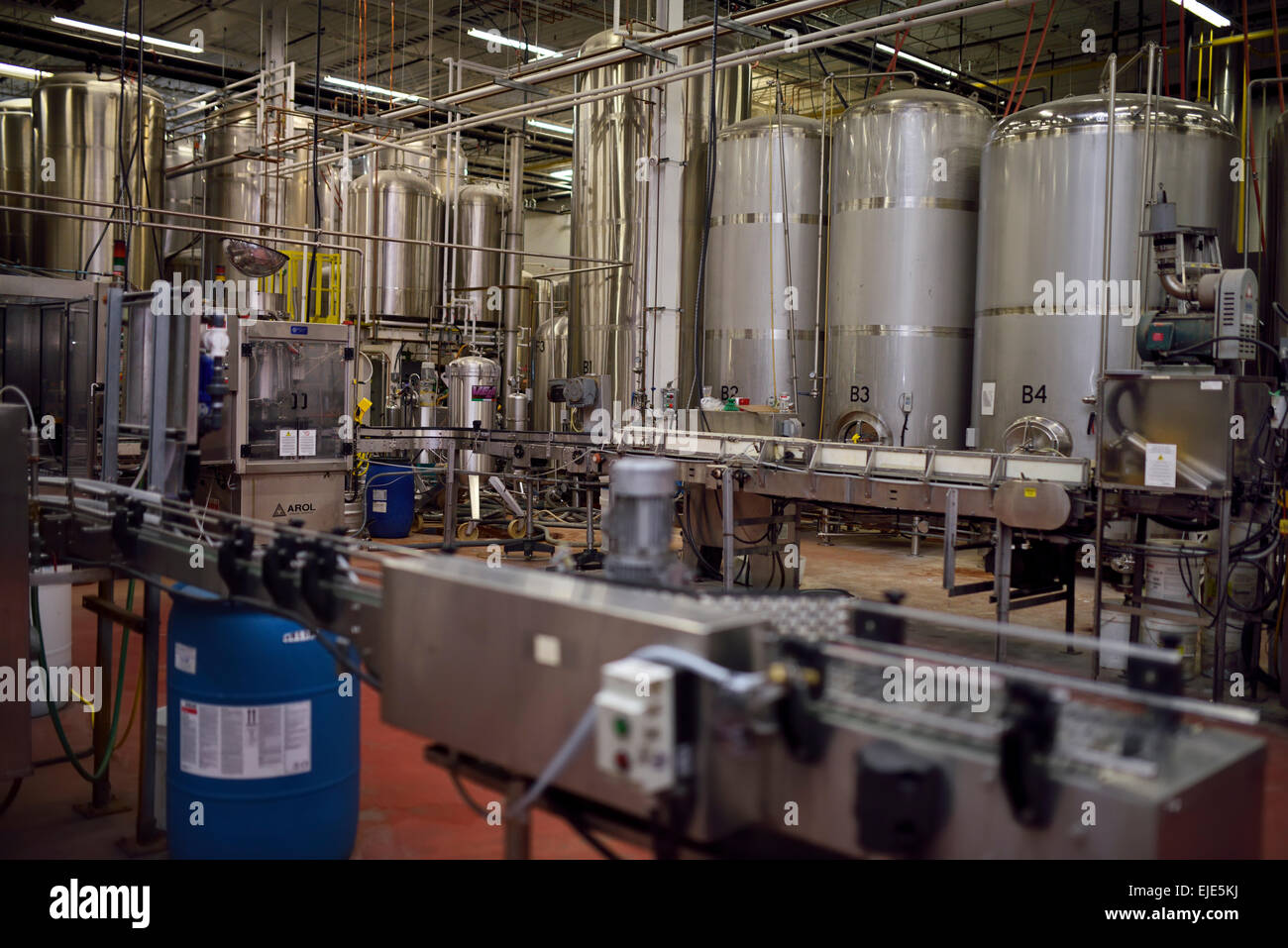Beer assembly line conveyor belt and brewing tanks in a brewery plant Toronto Stock Photo