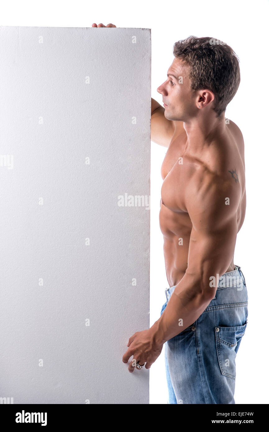 Strong muscular young man next to blank vertical white banner looking copyspace for your text, on white Stock Photo