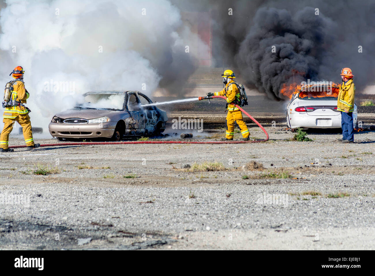 Burbank, California, USA. 24th March, 2015.  A firefighter attemping to put out car fires at the Triennial Full Scale Emergency Exercise  at Bob Hope  Airport as cars burn in the background. Credit:  Chester Brown/Alamy Live News Stock Photo
