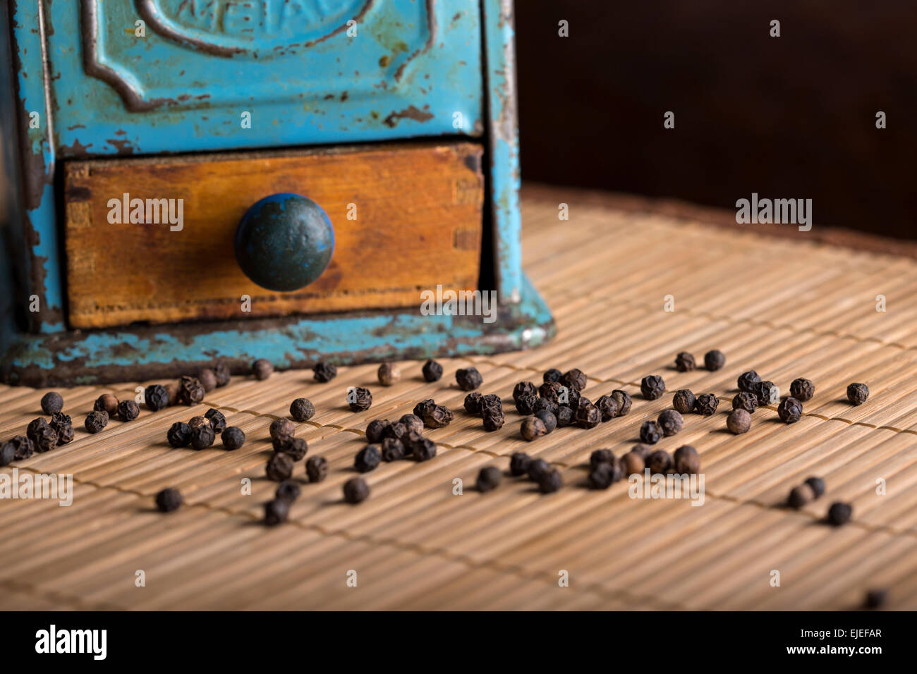 Vintage grinder with pepperon a wooden tablecloth,  close-up Stock Photo