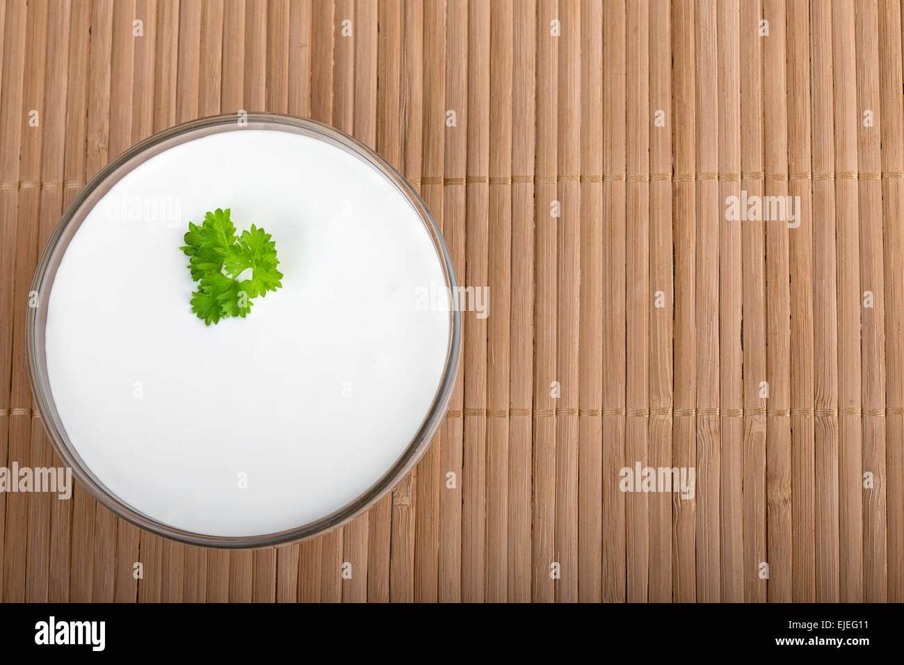 Bowl of sour cream on wooden tablecloth, top view Stock Photo