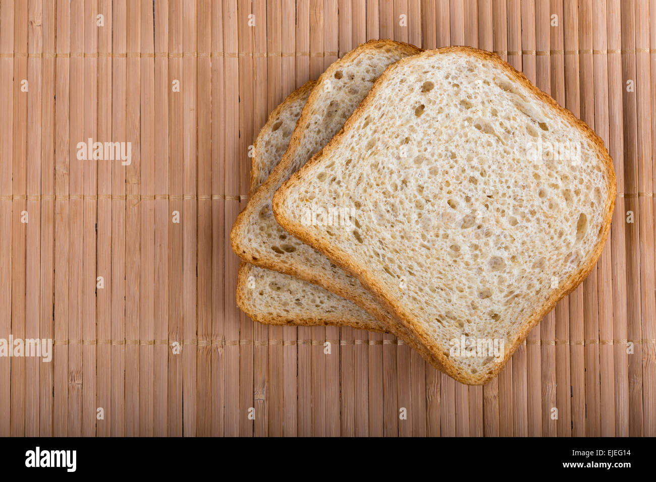 Slices of white bread on a wooden tablecloth, top view Stock Photo
